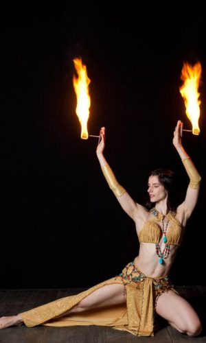 Feuertänzerin bei einer Feuershow. Zwei Fackeln in der Hand Geschichte des Feuers
